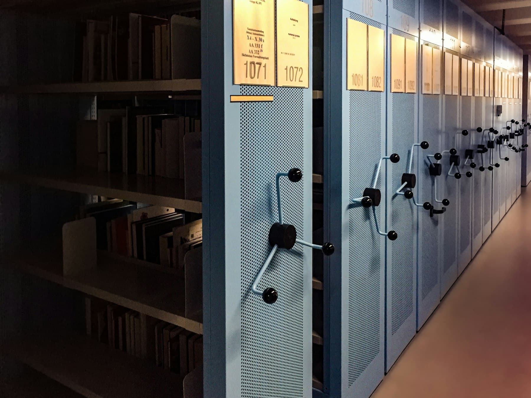 Arxiv rəflərinin sıx cərgəsi: oxra rəngli etiketlərlə nişanlanmış sənəd qovluqları